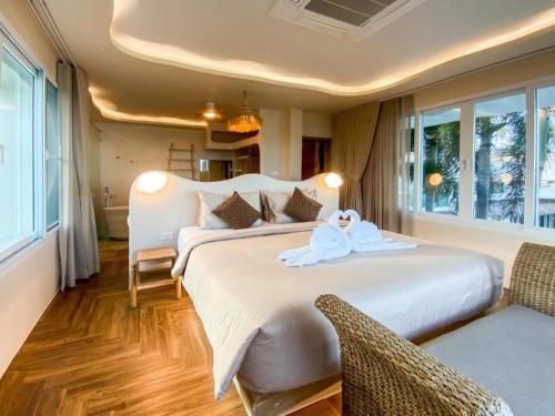 a bedroom with a large bed with towels on it at The Rock Samui Beachfront Villas - Sha Plus Hotel in Lamai