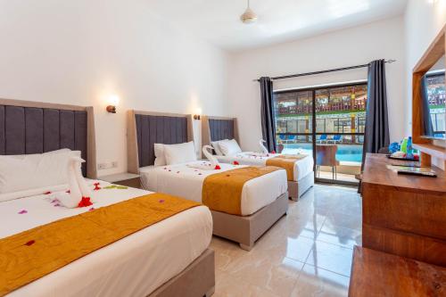 ein Hotelzimmer mit 3 Betten und einem TV in der Unterkunft Canary Hotel & SPA in Nungwi