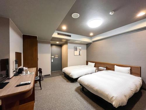 a hotel room with two beds and a desk at Hotel Route-Inn Dai2 Nagano Naganobekkan in Nagano