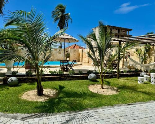 twee palmbomen in het gras naast een zwembad bij Pousada Coconut Cumbuco in Cumbuco