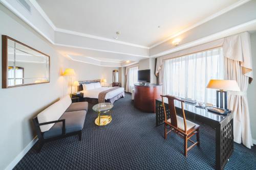 倉敷市にある倉敷ロイヤルアートホテルのベッドとデスクが備わるホテルルームです。