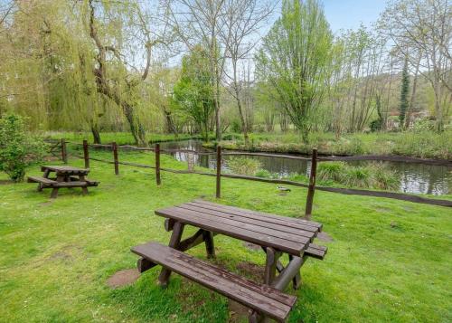 two picnic tables in a park next to a pond at Tilford Woods Lodge Retreat in Farnham