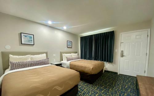 a hotel room with two beds and a window at The Grove at Pismo Beach in Pismo Beach