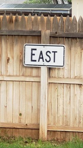 a street sign that reads east next to a fence at Hot Tub, Privacy, sleeps 11 & TONS of Space! in Lubbock