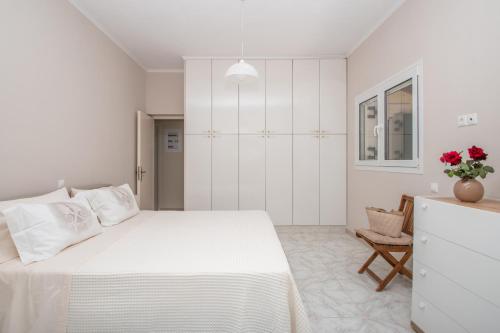 a white bedroom with a large bed and a chair at Korfoula Residence - Peaceful retreat in Zante in Koiliomenos