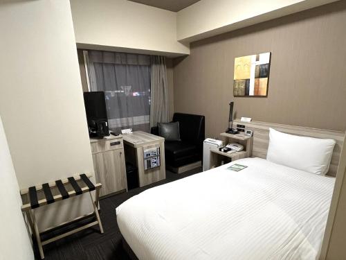 um quarto de hotel com uma cama e uma cadeira em Hotel Route Inn Takamatsu Yashima em Takamatsu