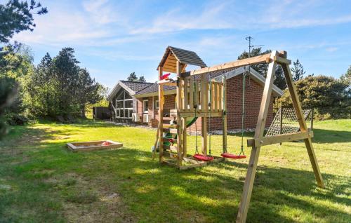 a wooden swing set in a yard with a house at Amazing Home In Blåvand With Kitchen in Blåvand