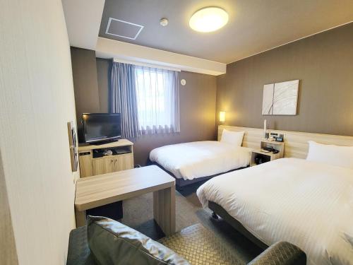 a hotel room with two beds and a television at Hotel Route-Inn Komoro in Komoro