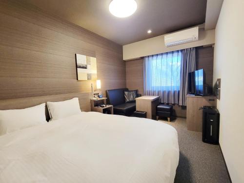 a hotel room with a white bed and a television at Hotel Route-Inn Komoro in Komoro