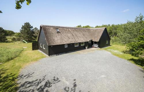 a black barn with a roof on a road at Amazing Home In Rømø With Sauna in Toftum