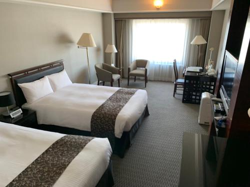 a hotel room with two beds and a window at Kurashiki Royal Art Hotel in Kurashiki
