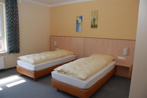 two beds sitting in a room with at Pension Alram Hof in Eggenfelden