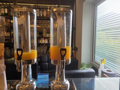 two blenders sitting on a counter with orange juice at The Gatwick White House Hotel in Horley