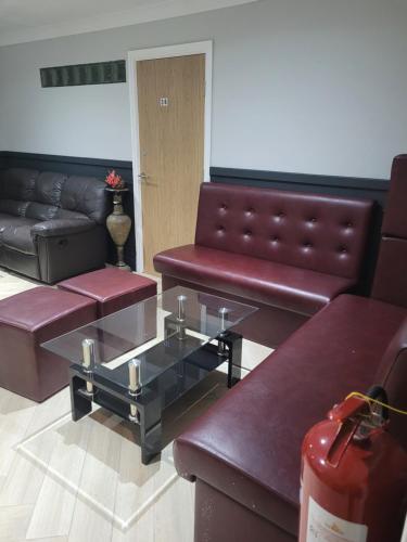 a living room with leather couches and a glass coffee table at The Gatwick White House Hotel in Horley
