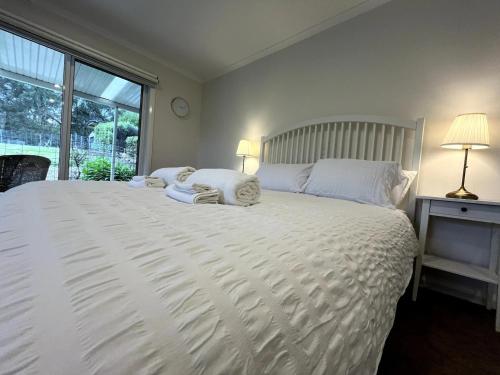 a bedroom with a large white bed with a window at Unicorn Farm-Tranquil Sauna Farmstay Escape in Magpie