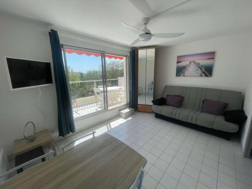 un salon avec un canapé et une grande fenêtre dans l'établissement Studio rénové avec loggia, parking privé et proche plage - Quartier calme - FR-1-328-267, à La Grande Motte