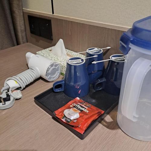 a table with a bottle of water and two blue vases at Urban Inn, Myra Meranti in Cyberjaya