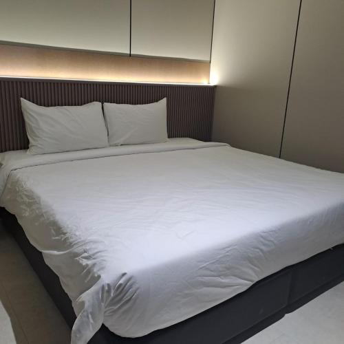 a large white bed with white sheets and pillows at Urban Inn, Myra Meranti in Cyberjaya