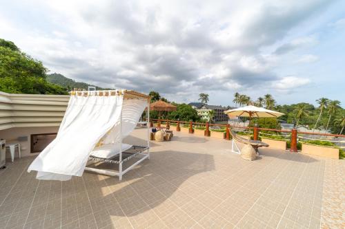 a patio with a white canopy and a swing at The Rock Samui Beachfront Villas - Sha Plus Hotel in Lamai