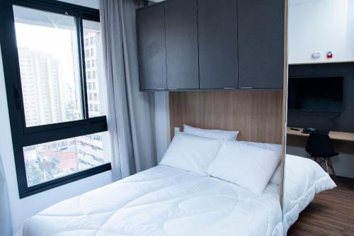 a bedroom with a white bed and a large window at ST Studios Vila Mariana by Housi in Sao Paulo