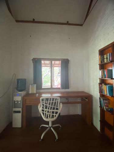 una scrivania con una sedia in una stanza con una finestra di BIG K HOSTEL a Karimunjawa