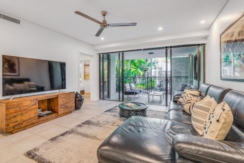 a living room with a leather couch and a flat screen tv at Resort-style Swim Out - A Poolside Oasis in Port Douglas