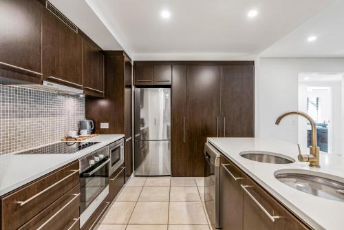 a kitchen with wooden cabinets and a sink at Resort-style Swim Out - A Poolside Oasis in Port Douglas