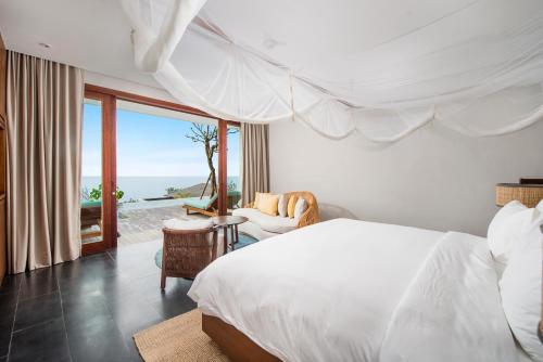 a bedroom with a bed and a view of the ocean at Six Senses Uluwatu in Uluwatu