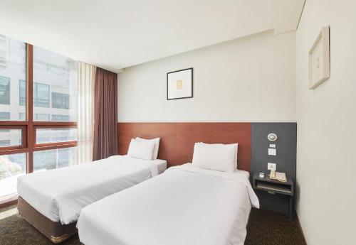a hotel room with two beds and a window at Hotel Skypark Kingstown Dongdaemun in Seoul