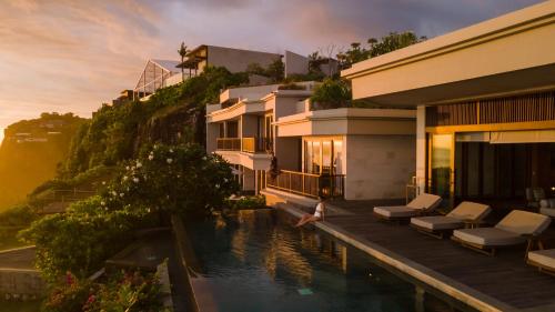 a villa with a swimming pool next to a house at Six Senses Uluwatu in Uluwatu