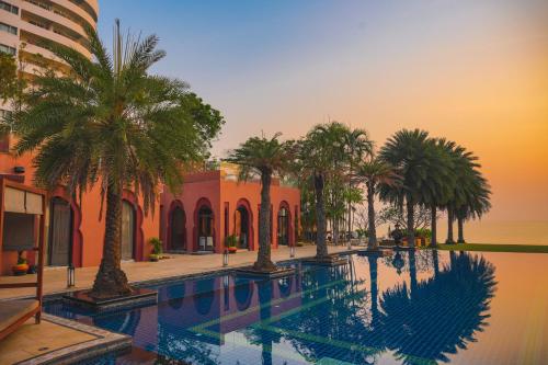 a swimming pool with palm trees in front of a building at Marrakesh Hua Hin Resort & Spa in Hua Hin