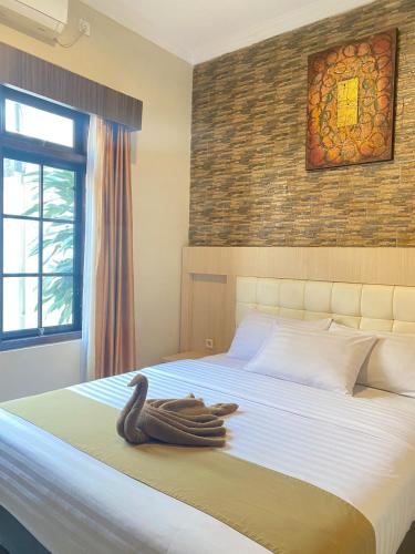 a large bed with a wooden swan decoration on it at Ayuri Hotel Malioboro in Sentool