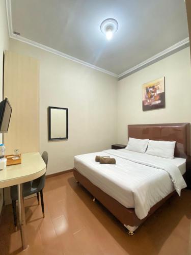a bed in a room with a desk and a bed sidx sidx sidx at Ayuri Hotel Malioboro in Sentool