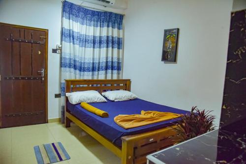 a bedroom with a bed with blue sheets and a window at Chill Airport Transit Stay in Katunayake
