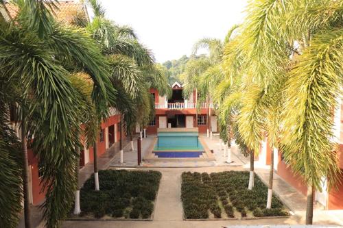 a building with a swimming pool and palm trees at Hornbillbay Beach Resort in Kampung Teluk Nipah