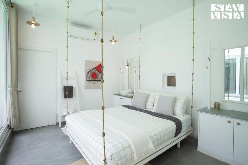 a white bedroom with a swinging bed in it at StayVista at Reflection by The Woods - Breakfast Included in Madikeri
