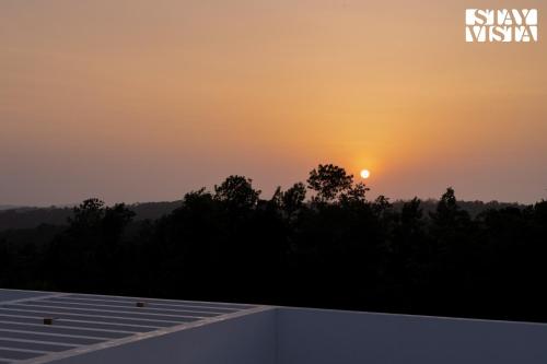 a sunset from the roof of a house at StayVista at Reflection by The Woods - Breakfast Included in Madikeri