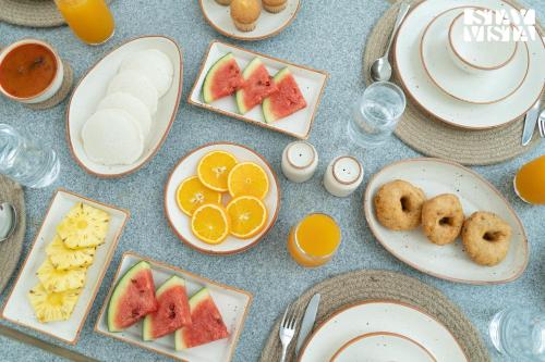 a table topped with plates of food with fruits and cookies at StayVista at Reflection by The Woods - Breakfast Included in Madikeri