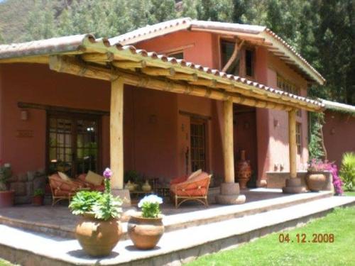 a house with a porch with potted plants in front of it at Karina Wasi in Pisac