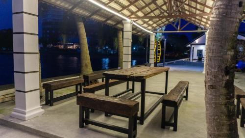 a table and benches in a building with a view at The Bay PD Beachfront Villa in Port Dickson