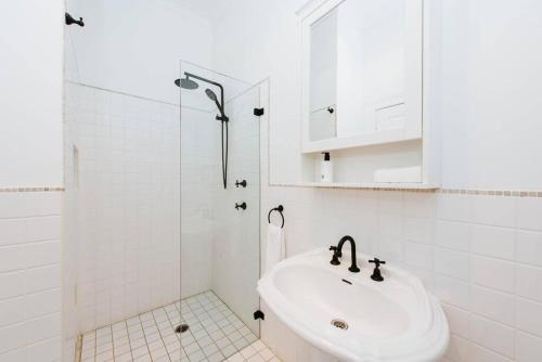 Un baño blanco con lavabo y ducha. en Kareela Cottage - A Charming Country Getaway, en Mudgee
