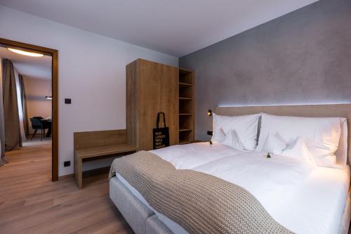 a bedroom with a large white bed and a mirror at Quality Hosts Arlberg - AFOCH FEI - das Landhaus in Sankt Anton am Arlberg
