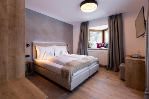 a bedroom with a large bed and a window at Quality Hosts Arlberg - AFOCH FEI - das Landhaus in Sankt Anton am Arlberg