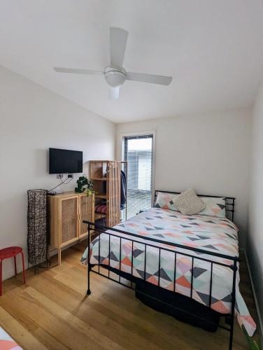 a bedroom with a bed and a flat screen tv at Kutu Ev in Apollo Bay