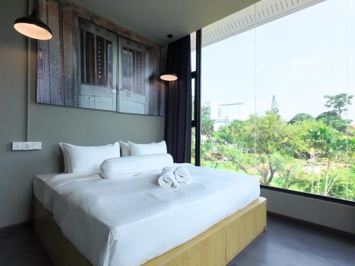 a bedroom with a large white bed with a large window at Rucksack Inn Premium Melaka in Melaka