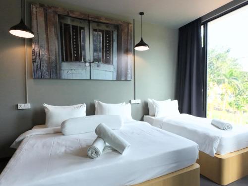 two white beds in a room with a window at Rucksack Inn Premium Melaka in Melaka