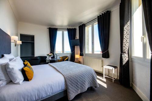 a hotel room with a bed and windows at La Villa Andry in Ouistreham