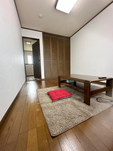 a room with a table and a red pillow on a rug at Kei Chia Private Lodging in Kurihashi