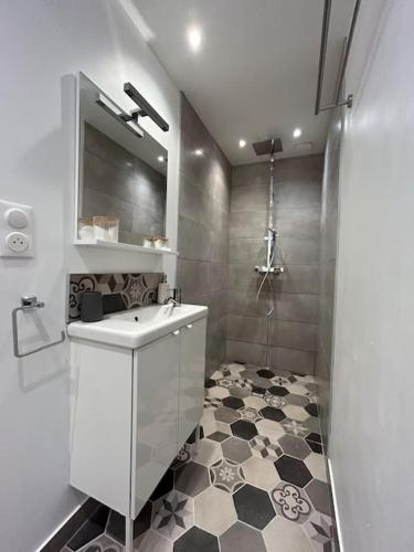 La salle de bains est pourvue d'un lavabo blanc et d'un sol noir et blanc. dans l'établissement Appart 4 personnes Béthune Centre, à Béthune