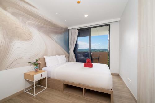 une chambre avec un lit blanc et une fenêtre dans l'établissement Greenery Views 1 BR Laguna SkyLine Apartment B2512 just 10 min walk Bangtao Beach, à Laguna Phuket